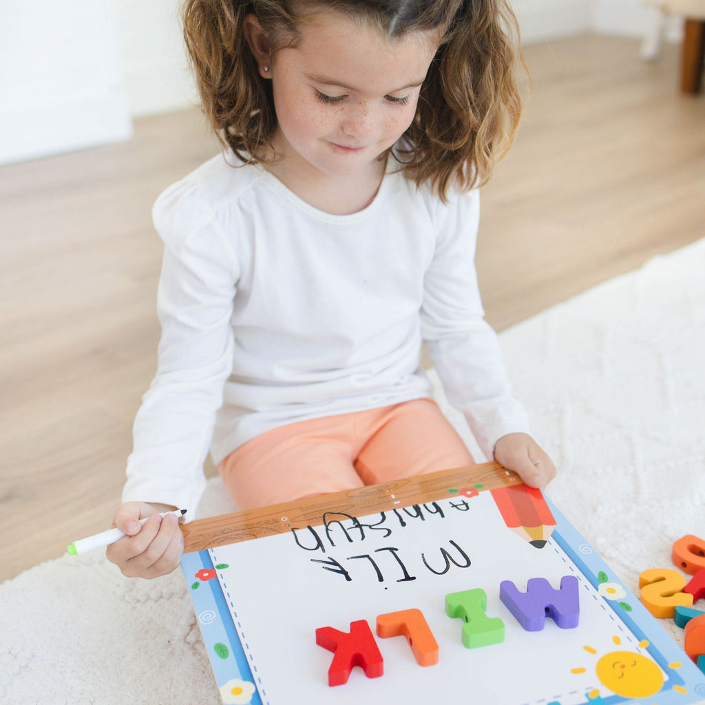 Child playing with colorful letters on a whiteboard