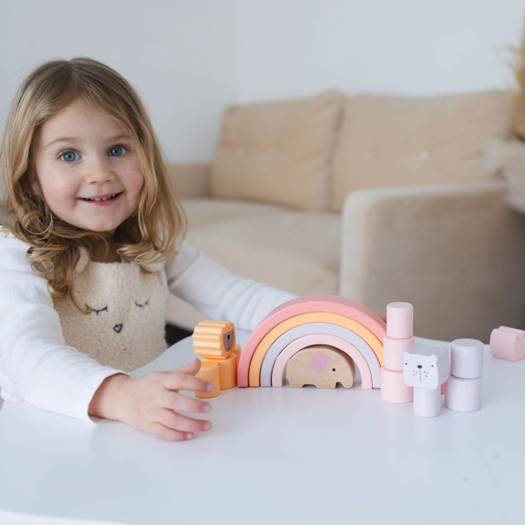 Child playing with colorful pastel building blocks on a table in a cozy living room.
