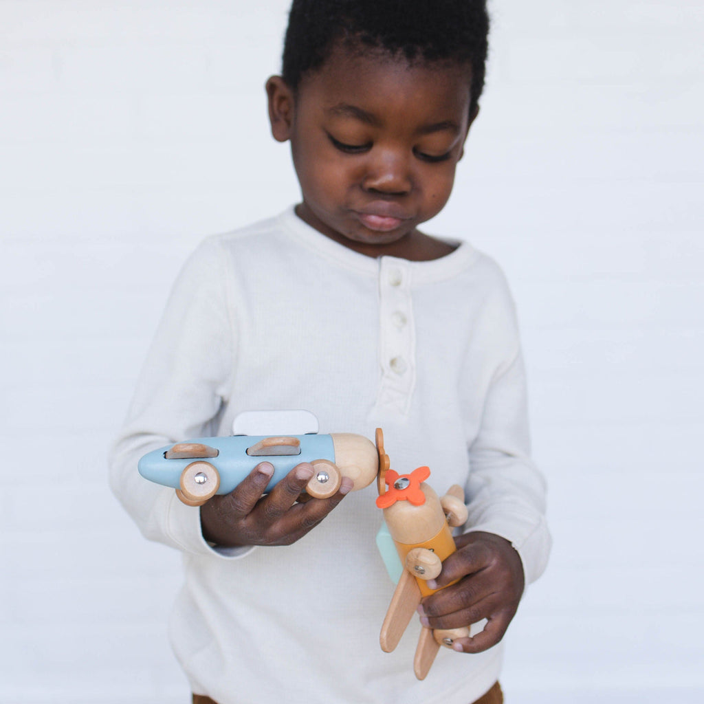Child holding a wooden toy with a plain background