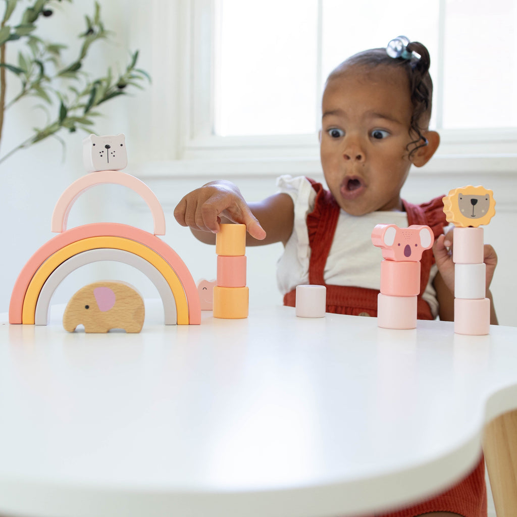 Child pointing at stacked wooden blocks on a table indoors