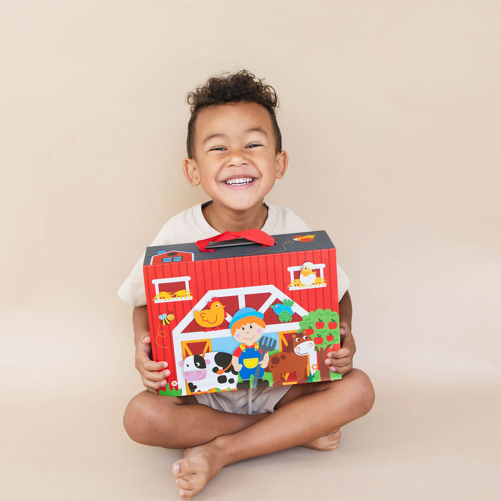Child holding a colorful toy barn set against a beige background