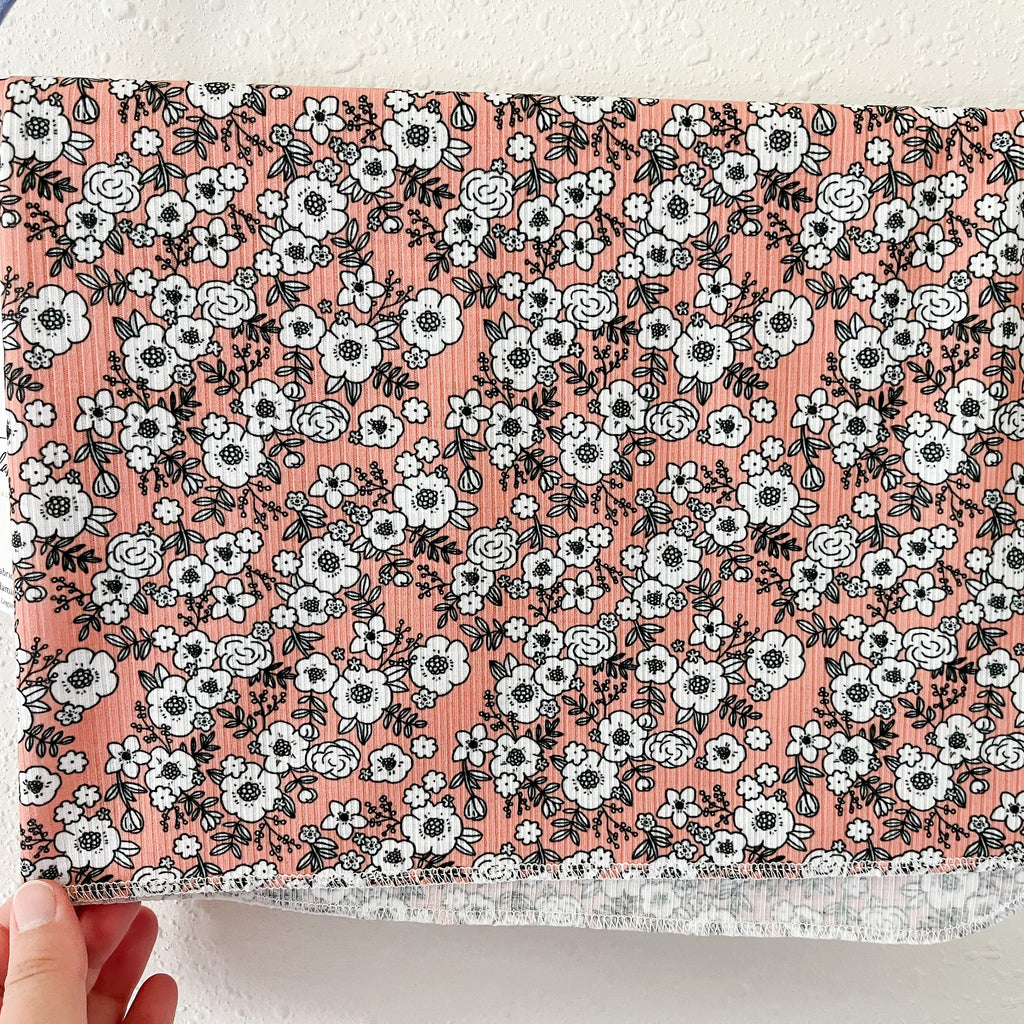 Floral-patterned blanket held against a neutral background