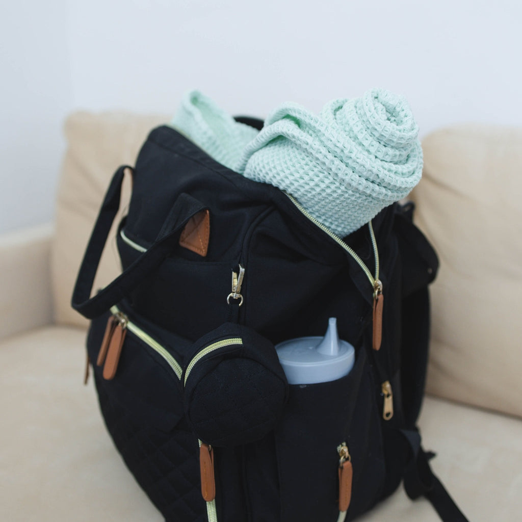blanket in backpack on a neutral couch